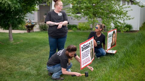 Lacey Ayers talks to Stacy Koester, left, and Melissa Bloxom as they place signs with an image of Irene Gakwa in a yard in Gillette, Wyoming. Gakwa lived next door with her boyfriend before her disappearance.