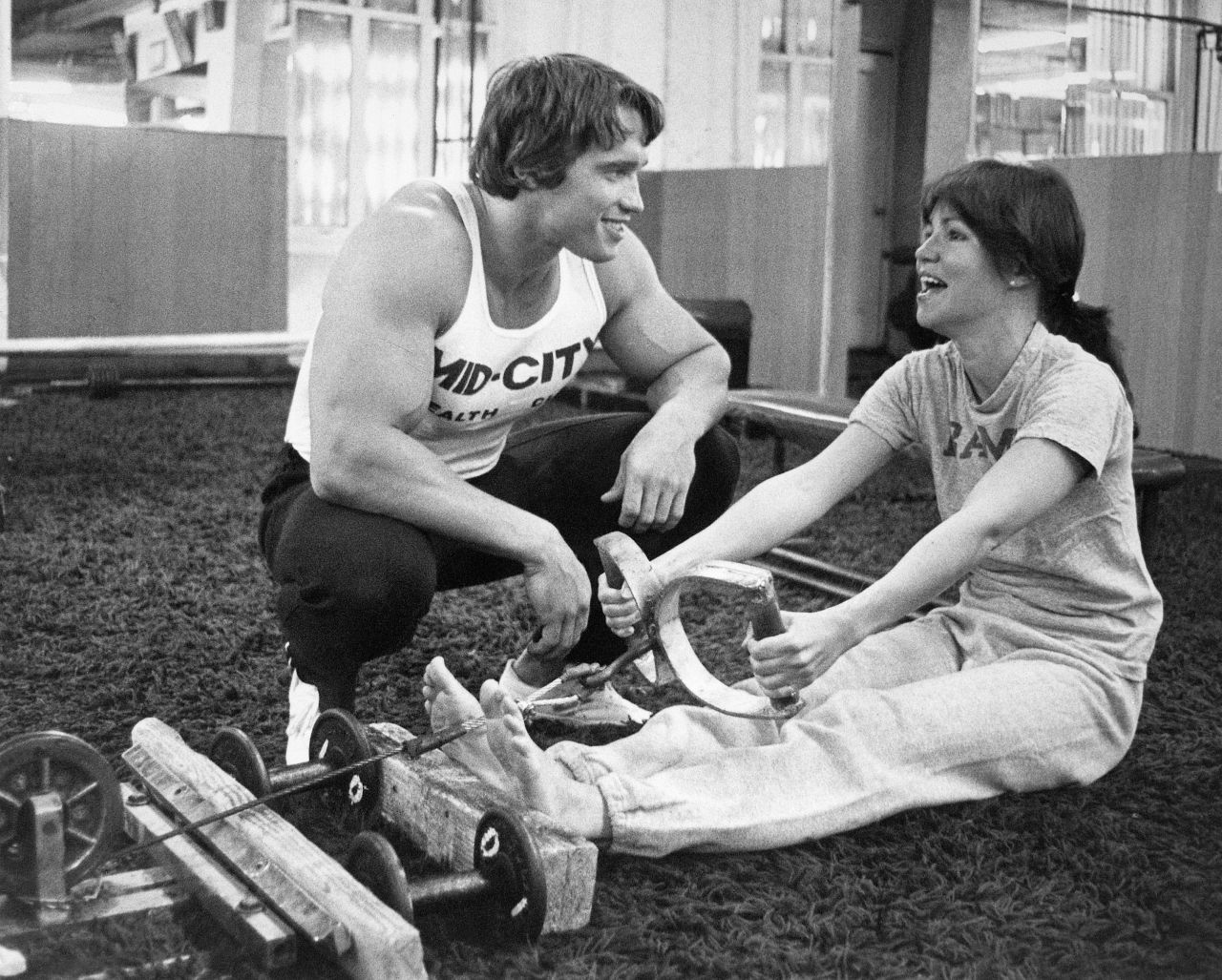 Field exercises on a row machine alongside Arnold Schwarzenegger in 1976. They began training together while working on the film "Stay Hungry."