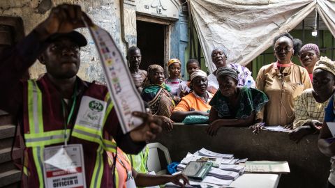 Orang-orang menyaksikan seorang pejabat Komisi Pemilihan Nasional Independen (INEC) mengangkat kertas suara selama proses penghitungan suara di TPS di Alimosho, Lagos, pada 25 Februari 2023.