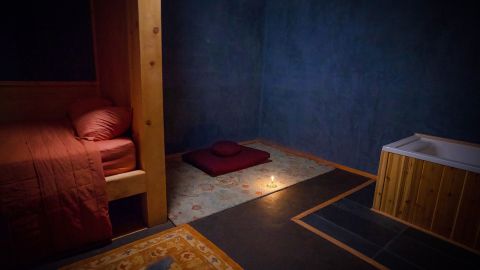 Each space contains a bed, a toilet, sink and a bathtub, as well as a low table for eating and a carpeted area for yoga and meditation.