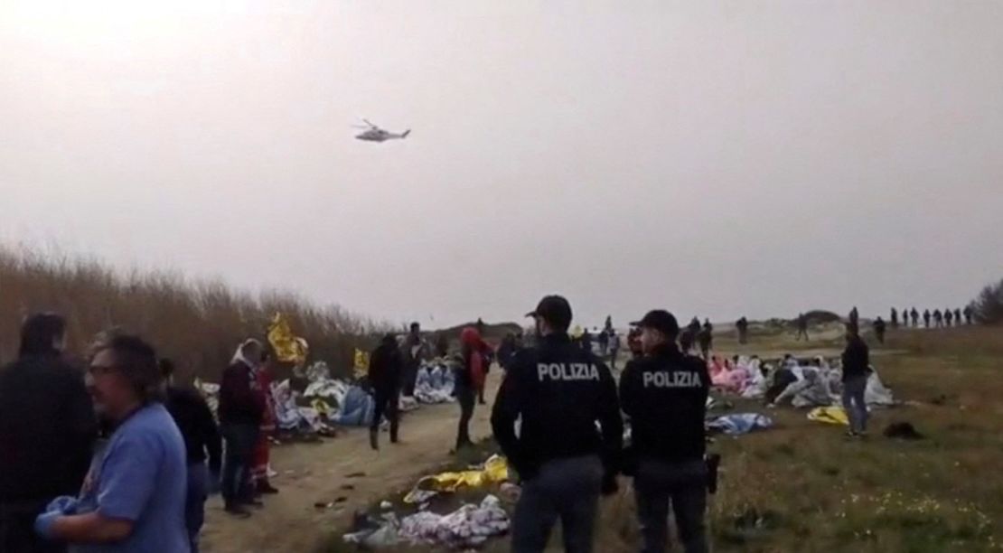 Police officers standing at the beach where bodies were found. One survivor has been arrested on migrant trafficking charges.