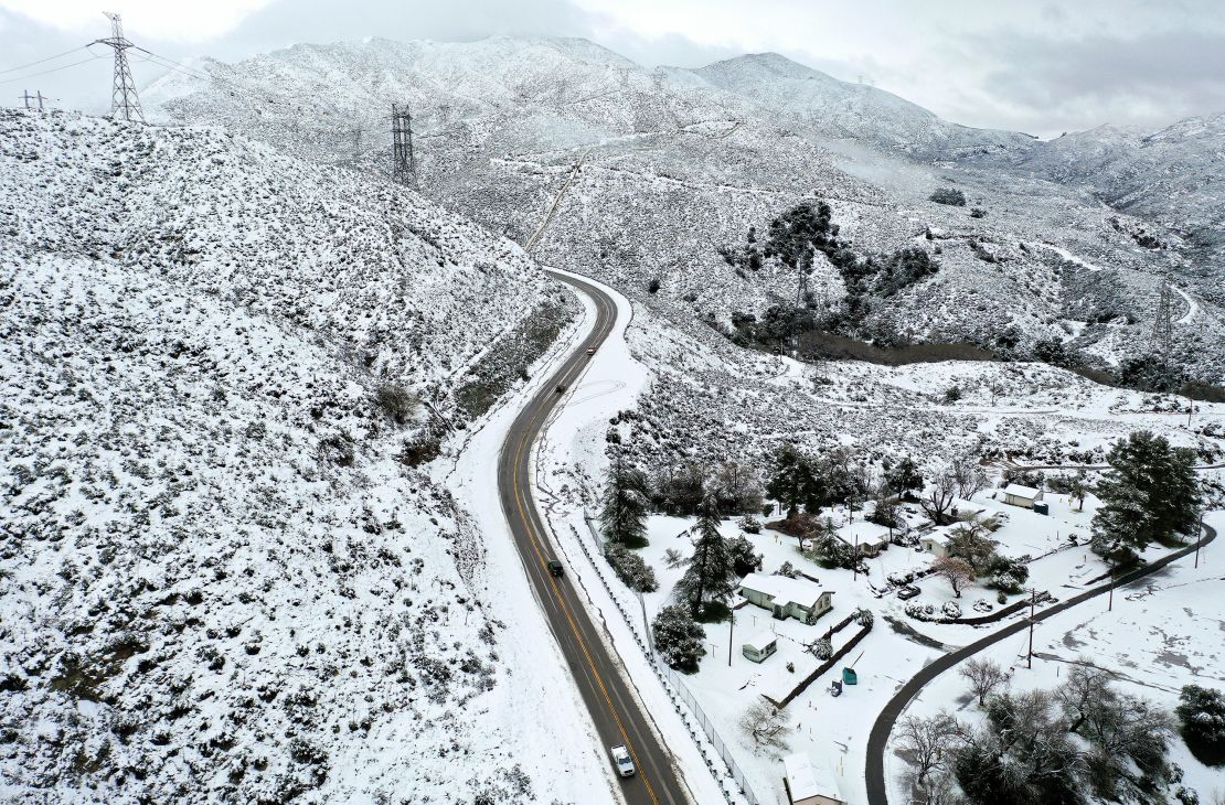 In an aerial view, drivers pass through the snow-covered Sierra Pelona Mountains in Los Angeles County. 