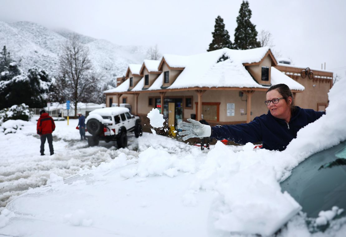 A person clears snow from their windshield in Los Angeles County, in the Sierra Pelona Mountains. 
