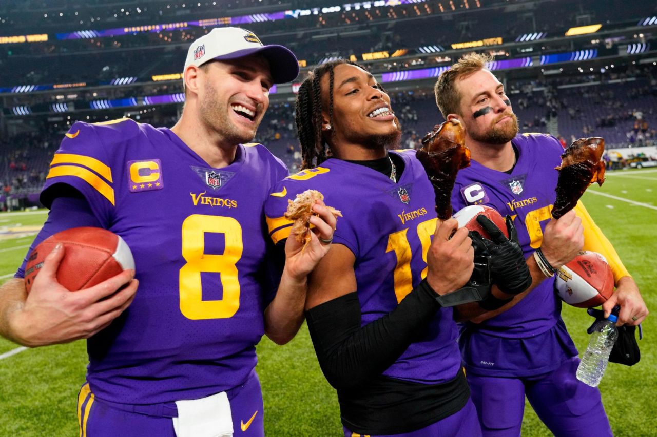 Minnesota Vikings trio Kirk Cousins, Justin Jefferson, and Adam Thielen celebrate a Thanksgiving Day victory over the New England Patriots in 2022 by eating turkey legs. The tradition is a homage to legendary coach John Madden, who awarded the first "Turkey Leg Award" to Thanksgiving Day MVP Reggie White in 1989, while working for CBS.