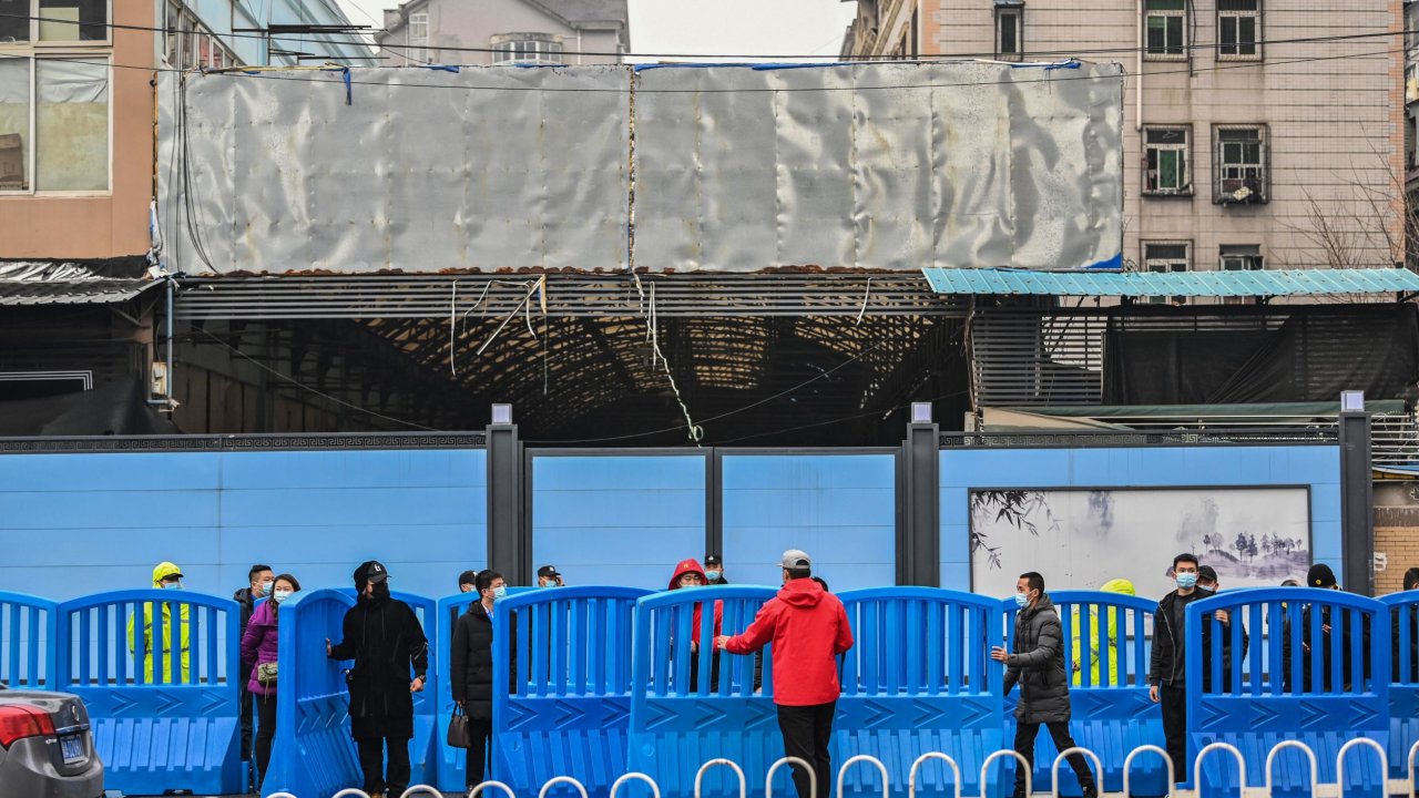 Workers place barriers outside the closed Huanan Seafood wholesale market during a visit by members of the World Health Organization (WHO) team, investigating the origins of the Covid-19 coronavirus, in Wuhan, China's central Hubei province on January 31, 2021. (Photo by Hector RETAMAL / AFP) (Photo by HECTOR RETAMAL/AFP via Getty Images)