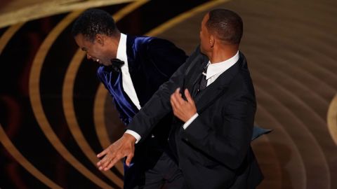 Will Smith, right, hits presenter Chris Rock on stage while presenting the award for best documentary feature at the Oscars on March 27, 2022.