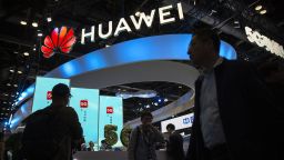 FILE - In this Thursday, Oct. 31, 2019 file photo, attendees walk past a display for 5G services from Chinese technology firm Huawei at the PT Expo in Beijing.