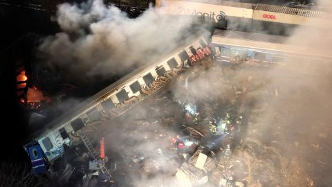 Smoke rises from the derailed train carriages.