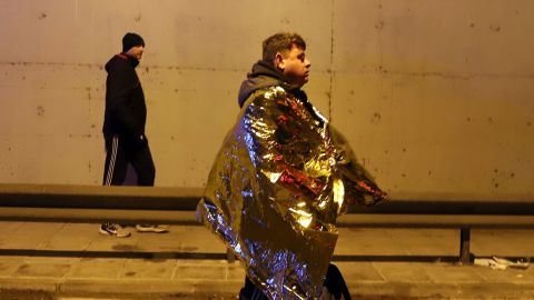 A passenger is seen walking on a road after the collision in Larissa city.