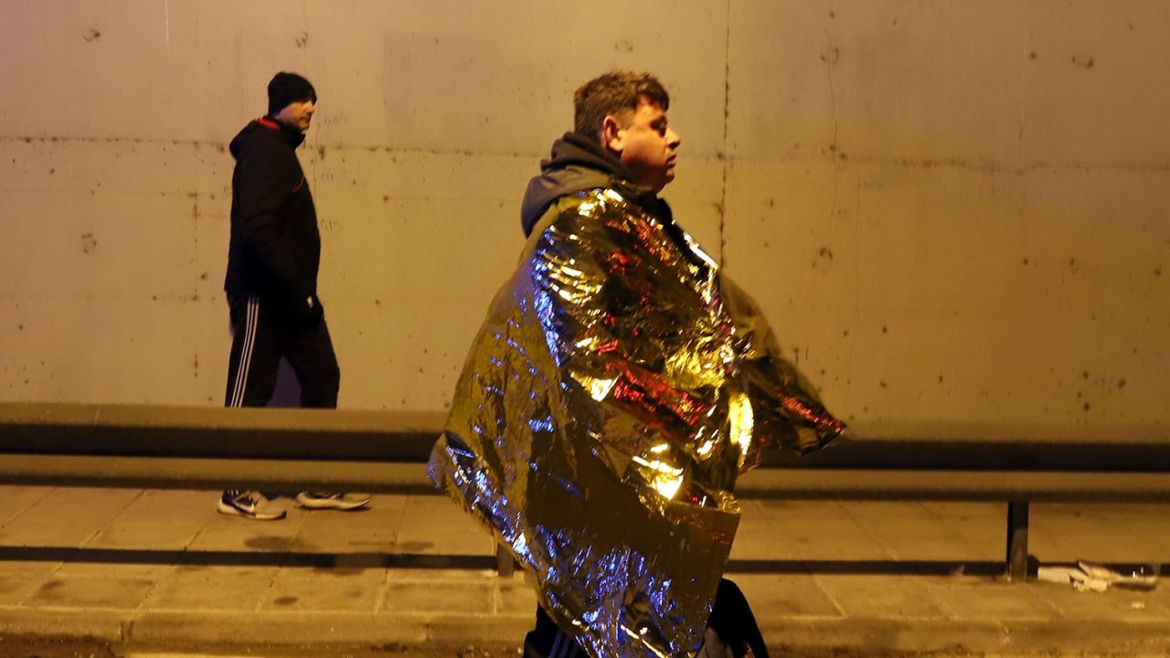 A passenger walks on the side of the road after the fatal crash in Larissa city.