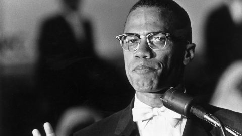 Malcolm X stands at a podium during a rally of African-American Muslims held in a Washington, DC arena, circa 1962. 