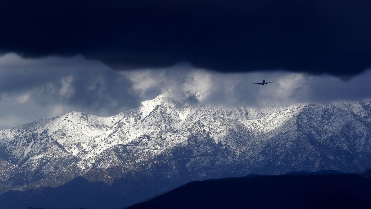 Snow-covered mountains serve as a backdrop for airplanes flying over the San Fernando Valley on Tuesday.