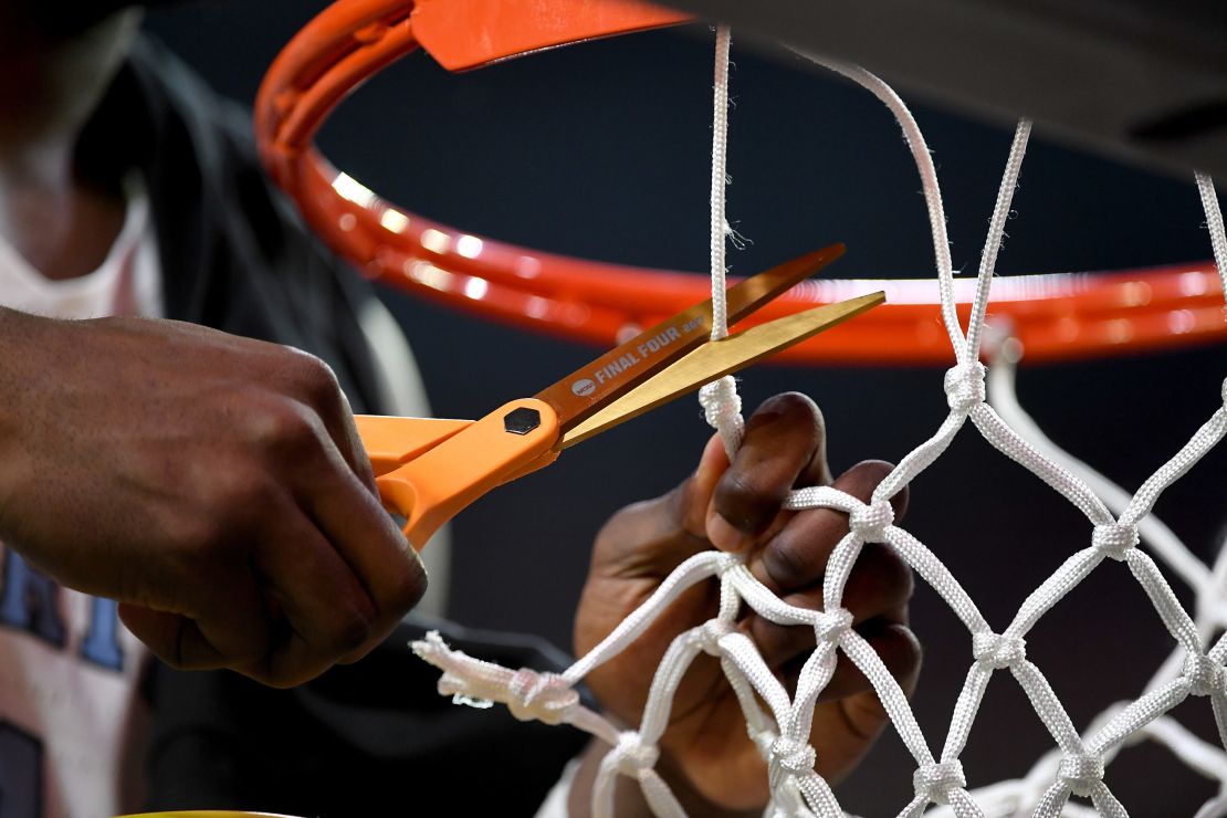 A North Carolina Tar Heels basketball player cuts a piece of the net during the 2017 March Madness. 