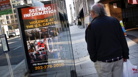 A local resident looks at a billboard with pictures of supporters of US President Donald Trump wanted by the FBI who participated in storming the US Capitol, forcing Congress to postpone a session certifying the results of the 2020 U.S. presidential election, in Washington, U.S., January 13, 2021. 
