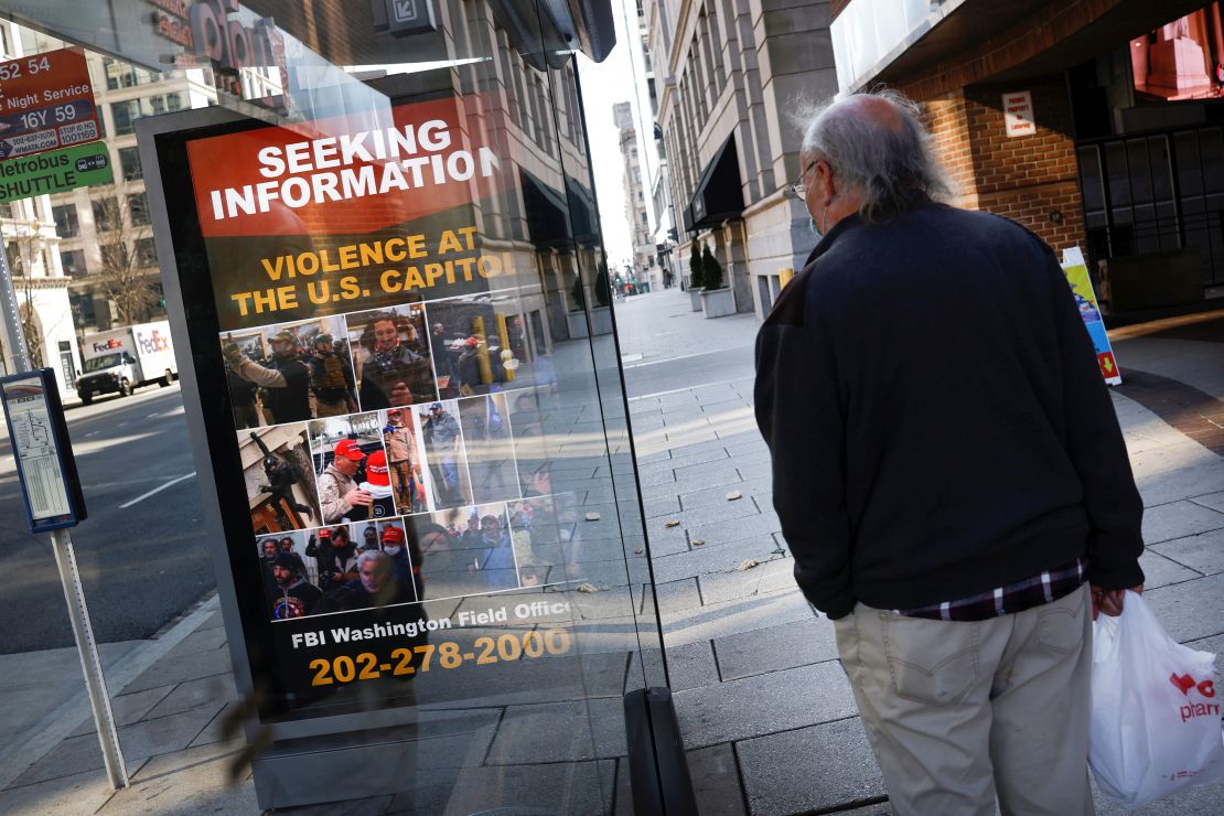 A local resident looks at a billboard with pictures of supporters of US President Donald Trump wanted by the FBI who participated in storming the US Capitol, forcing Congress to postpone a session certifying the results of the 2020 U.S. presidential election, in Washington, U.S., January 13, 2021. 