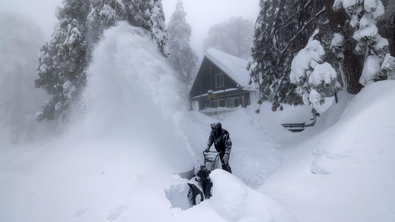A resident in the San Bernardino Mountains clears snow at his home on Wednesday, March 1, 2023, in Running Springs, California.