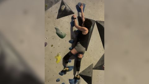 Bridges climbs a rock wall using prosthetic limbs.