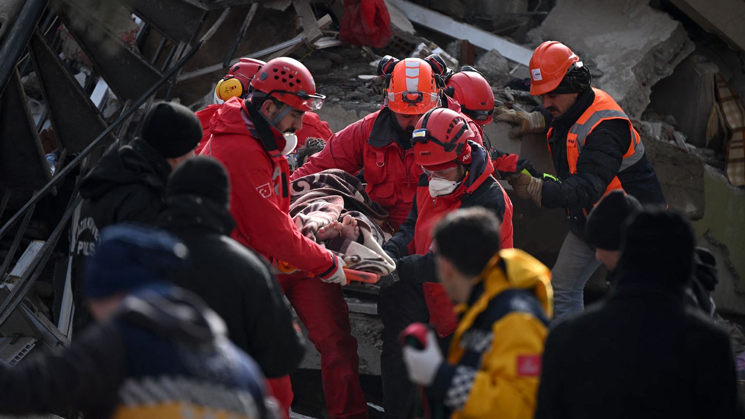 Rescue personnel carry a rescued young man on a stretcher through the rubble of buildings in Kahramanmaraş, the quake's epicenter, after a 7.8-magnitude earthquake struck the country's southeast on February 7. 