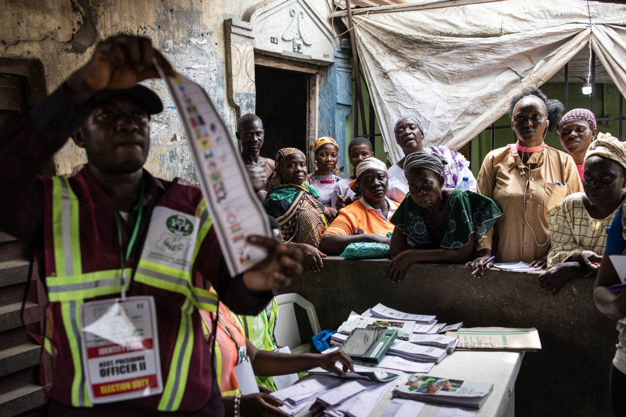 People watch as an election official holds up a ballot during the counting process for Nigeria's presidential election at a polling station in Lagos on Saturday, February 25. A Nigerian opposition party has said it will launch a legal challenge after Bola Ahmed Tinubu was declared the winner of the controversial elections on Wednesday.