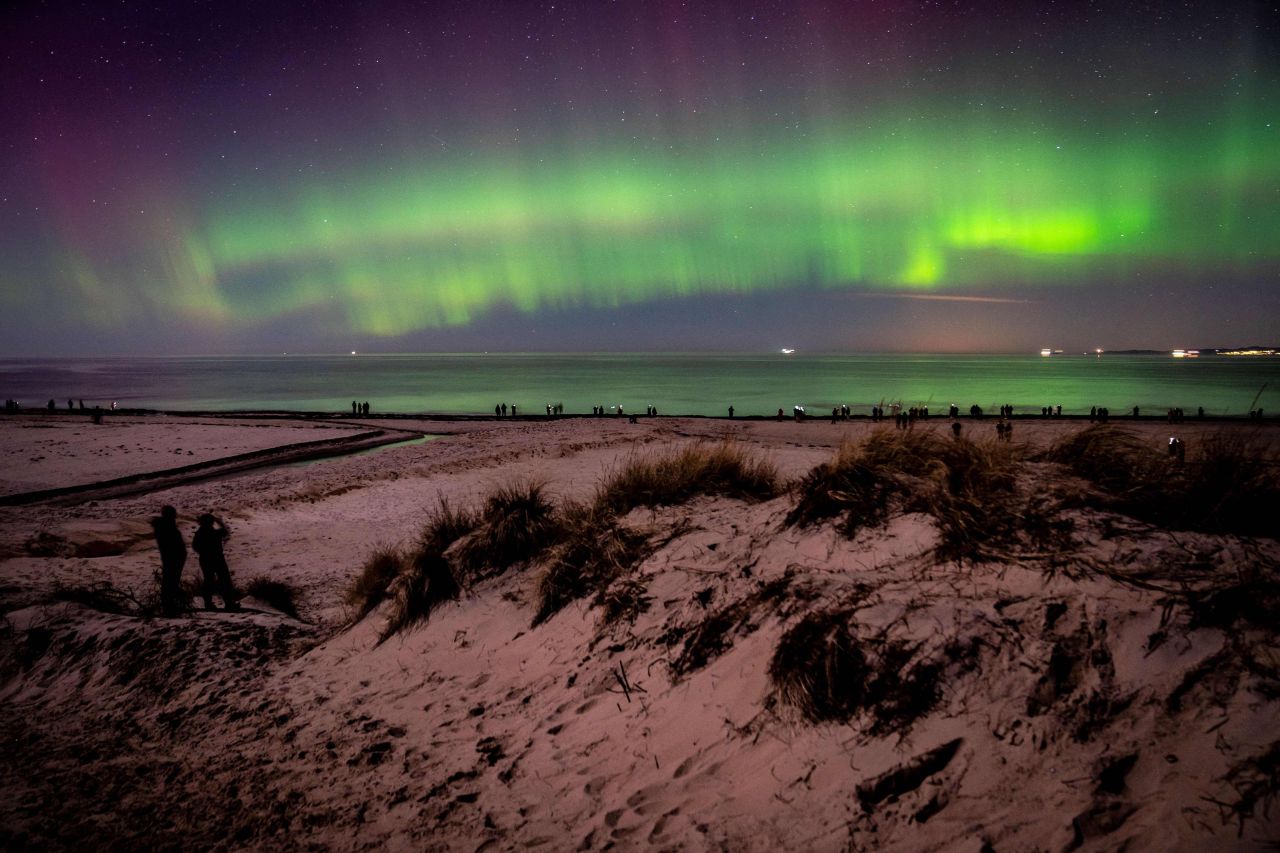 Northern lights illuminate the sky as visitors walk along Hornbaek Beach in the northern part of Sealand, Denmark, on Monday, February 27.
