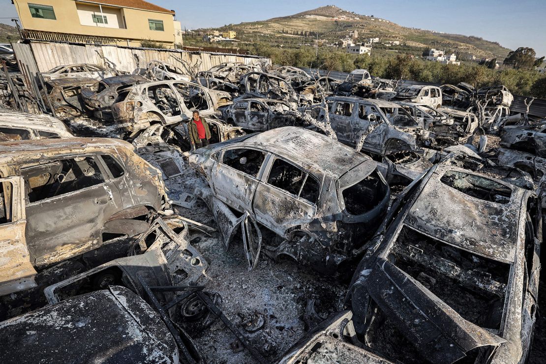 A man stands amidst destroyed cars at a scrapyard in the town of Huwara near Nablus in the occupied West Bank on Monday after they were torched overnight.