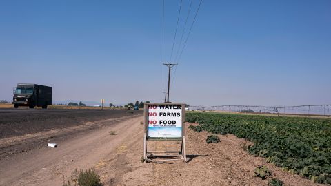 Traffic passes a sign reading "No Water, No Farms, No Food" near a pumpkin farm near Madras, Oregon, in August 2021.