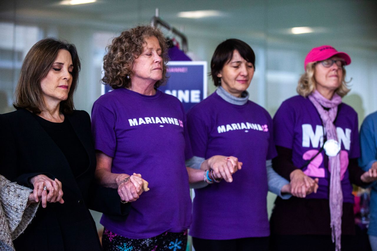 Williamson, left, holds hands with supporters in a moment of meditation in Iowa City in January 2020. She dropped out of the presidential race later that month.