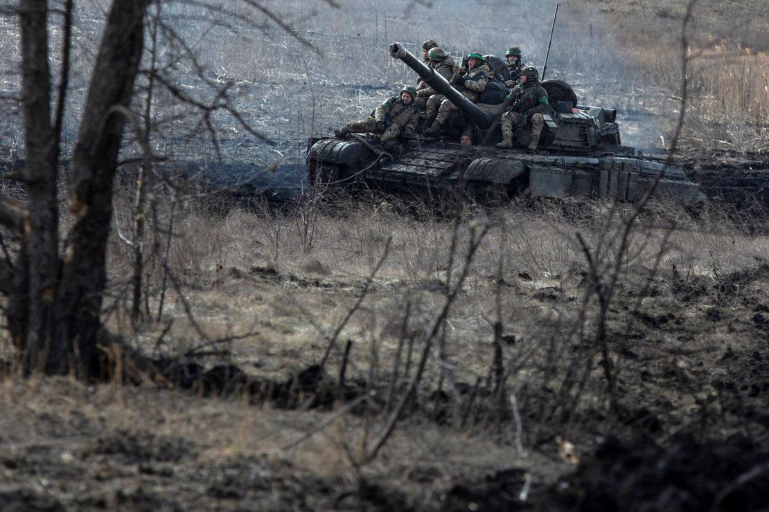 Ukrainian service members ride atop of a tank outside  Bakhmut, on March 4, 2023. 