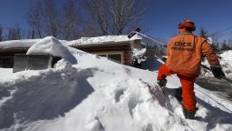 BIG BEAR LAKE, CA - MARCH 03: A Cal Fire Fenner Canyon fire crew inmate drags snow off the roof of a residence at a Big Bear Lake trailer park as the area digs out following successive storms which blanketed San Bernardino Mountain communities on Friday, March 3, 2023 in Big Bear Lake, CA. (Brian van der Brug / Los Angeles Times via Getty Images)