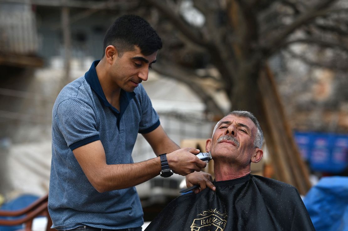 Ziya Sutdelisi, 53, a former local administrator, receives a free haircut from a volunteer from Gaziantep, in the village of Buyuknacar, near Pazarcik, Kahramanmaras province on Sunday, one month after a massive earthquake struck southeast Turkey.  