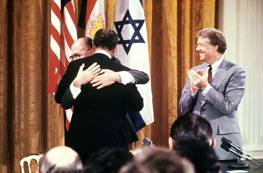 Carter claps as Sadat hugs Begin on September 17, 1978, after signing the peace agreement in the East Room of the White House. 