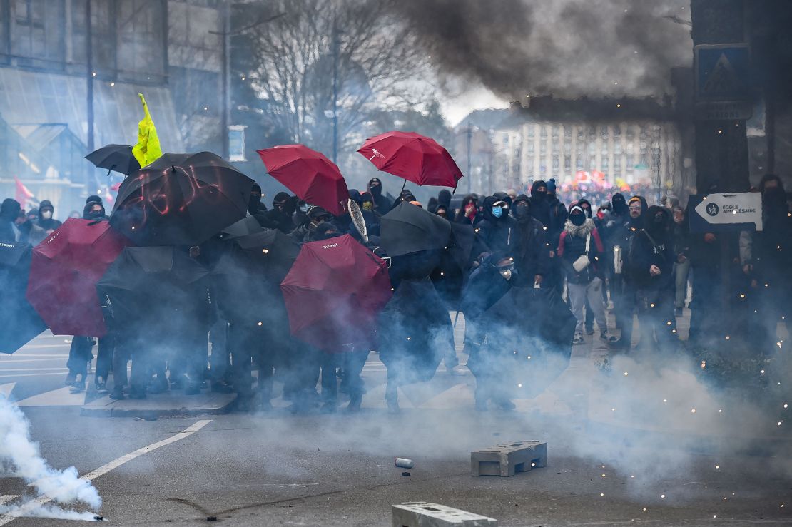 Protesters use umbrellas as protection against tear gas on the sidelines of a demonstration in Nantes, western France on March 7, 2023.