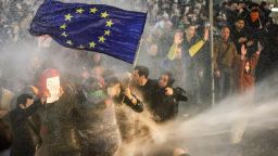TOPSHOT - Protesters brandishing a European Union flag brace as they are sprayed by a water canon during clashes with riot police near the Georgian parliament in Tbilisi on March 7, 2023. - Georgian police used tear gas and water cannon against protesters Tuesday as thousands of demonstrators took to the streets in the capital Tbilisi to oppose a controversial "foreign agents" bill. (Photo by AFP) (Photo by -/AFP via Getty Images)