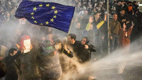 Protesters brandishing a European Union flag brace as they are sprayed by a water canon during clashes with riot police near the Georgian parliament in Tbilisi on March 7.