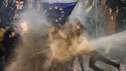 TOPSHOT - Protesters brandishing a European Union flag are sprayed by a water canon during clashes with riot police near the Georgian parliament in Tbilisi on March 7, 2023. - Georgian police used tear gas and water cannon against protesters Tuesday as thousands of demonstrators took to the streets in the capital Tbilisi to oppose a controversial "foreign agents" bill. (Photo by AFP) (Photo by -/AFP via Getty Images)