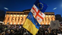 A protesters wave the Georgian, Ukrainian and European flags during a demonstration called by Georgian opposition and civil society groups outside Georgia's Parliament in Tbilisi on March 8, 2023. - At least two thousand demonstrators marched through the capital of Georgia, Tbilisi, on March 8, 2023 to protest government plans to introduce a "foreign agent" law reminiscent of Russian legislation used to silence critics. (Photo by Vano SHLAMOV / AFP) (Photo by VANO SHLAMOV/AFP via Getty Images)