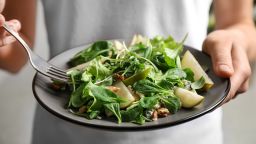 Woman with tasty pear salad on light background, closeup