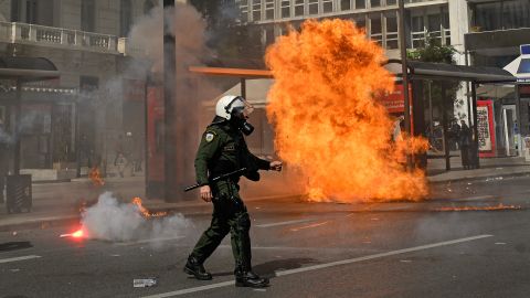 Un poliziotto antisommossa greco passa davanti a una molotov esplosa durante una manifestazione. 