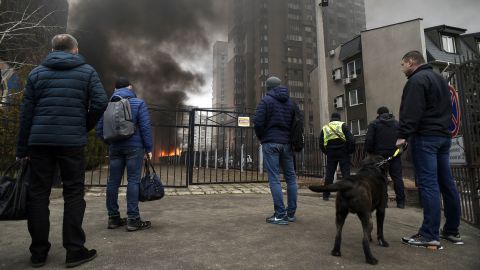 Los espectadores observan cómo se eleva el humo del fuego causado por los escombros de cohetes que caen en el patio de un edificio de apartamentos en el distrito de Sviatoshynskyi.