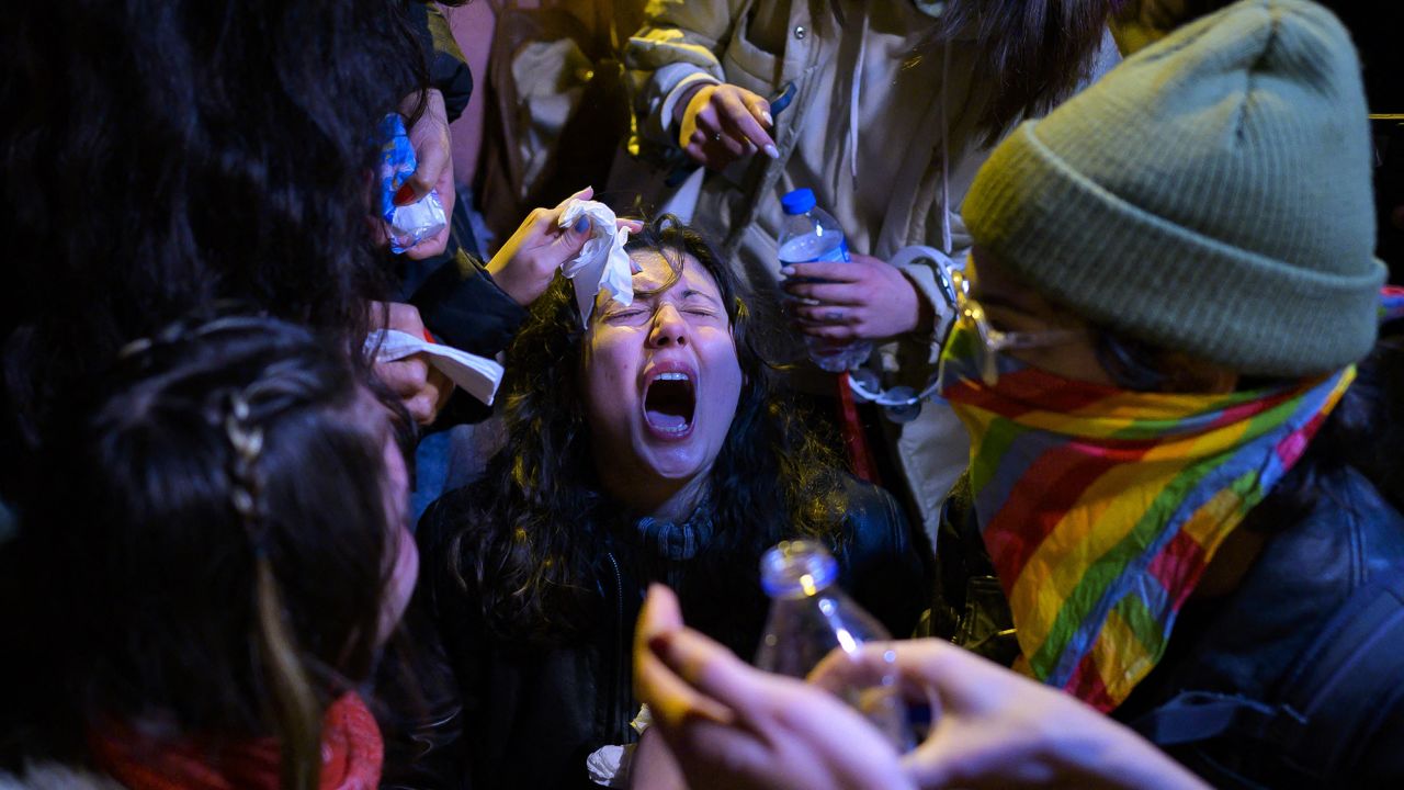 A woman is helped by other protesters after her eyes were burned as Turkish police used pepper spray during a march to Taksim Square, marking International Women's Day in Istanbul on March 8, 2023. 