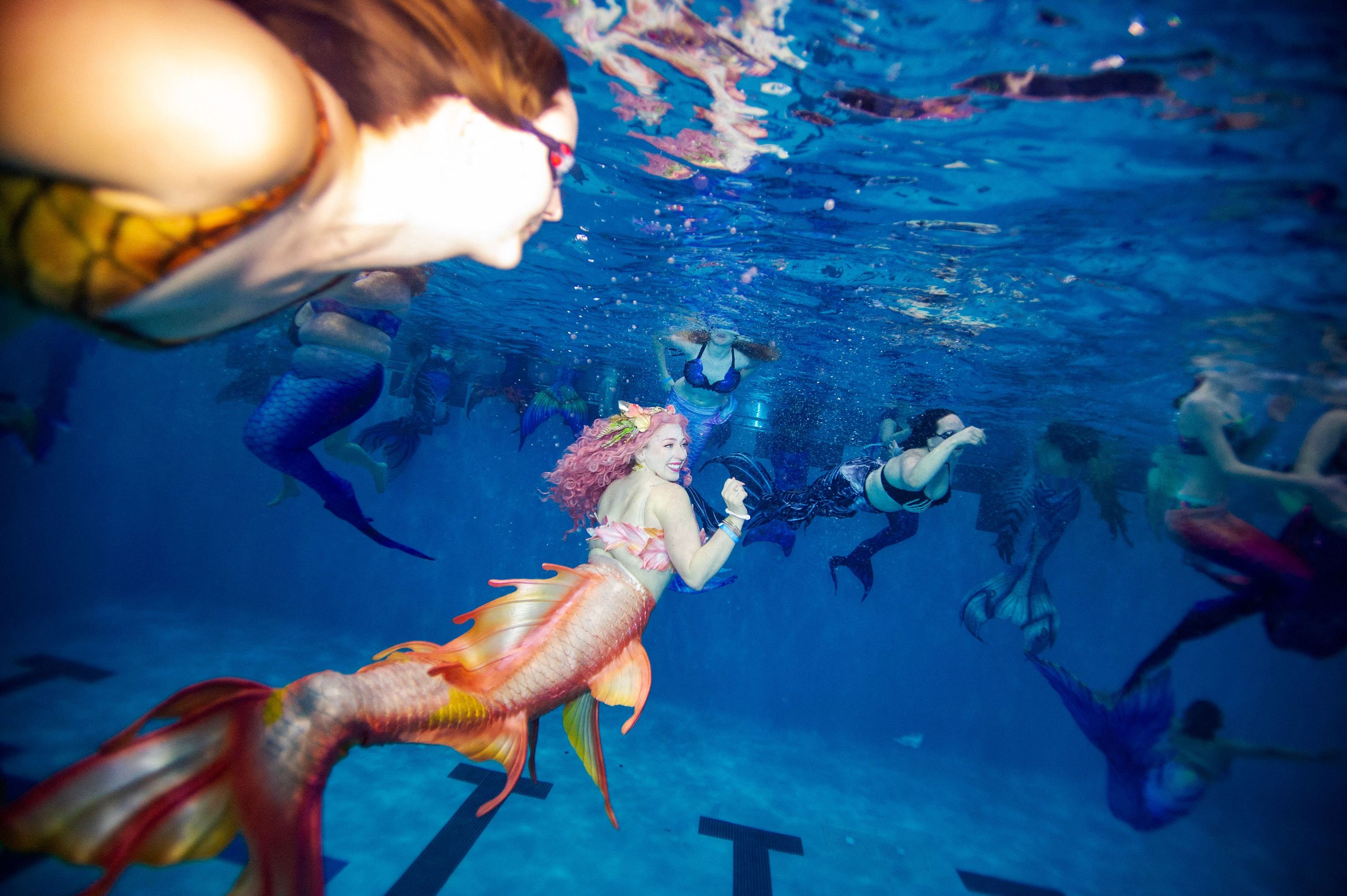 People dressed as mermaids and mermen take part in a group swim Saturday, March 4, during the MerMagic Convention in Manassas, Virginia.