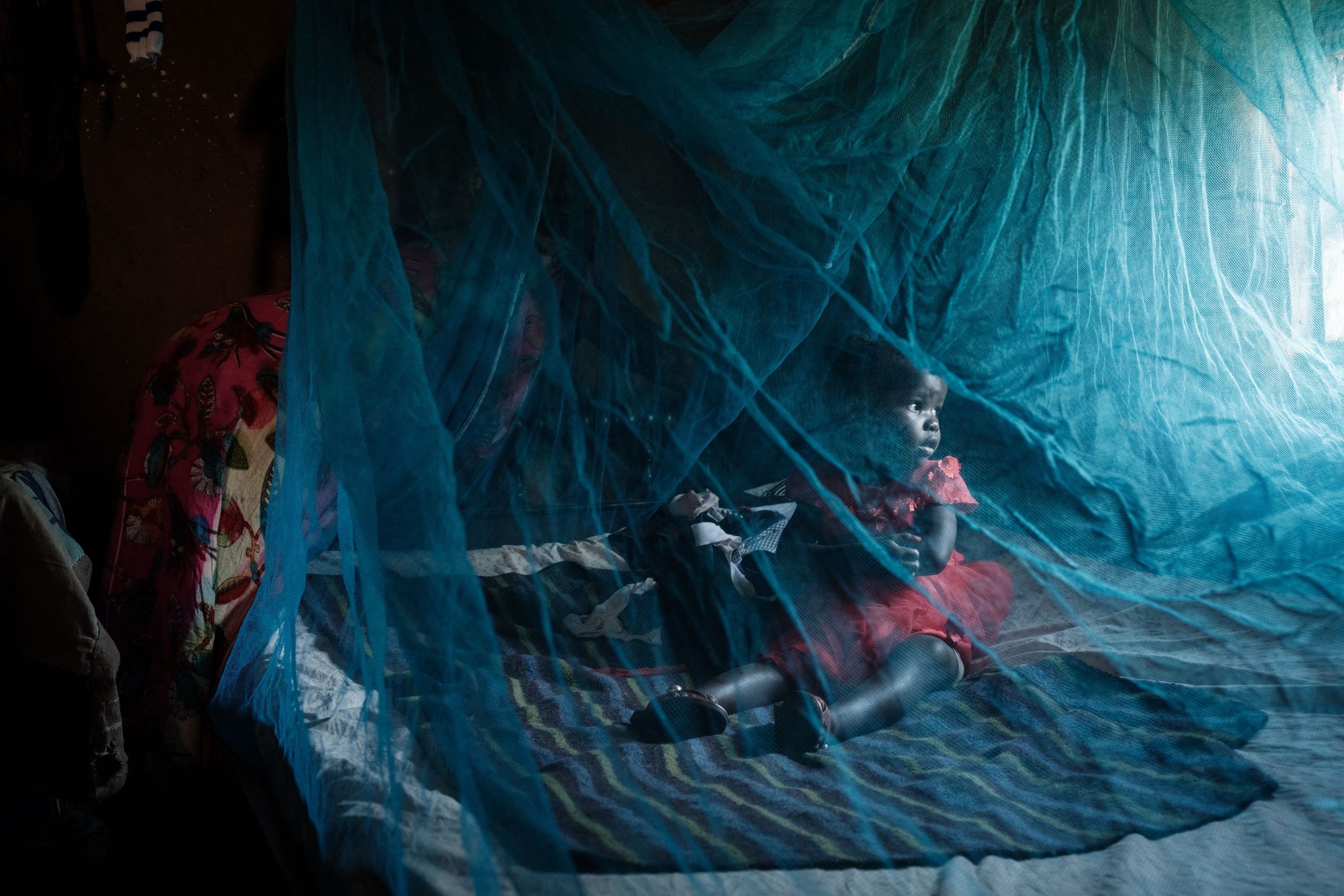 Ruth Kavere and her 3-year-old granddaughter Faith use a mosquito net at their home in Mukuli, Kenya, on Tuesday, March 7.