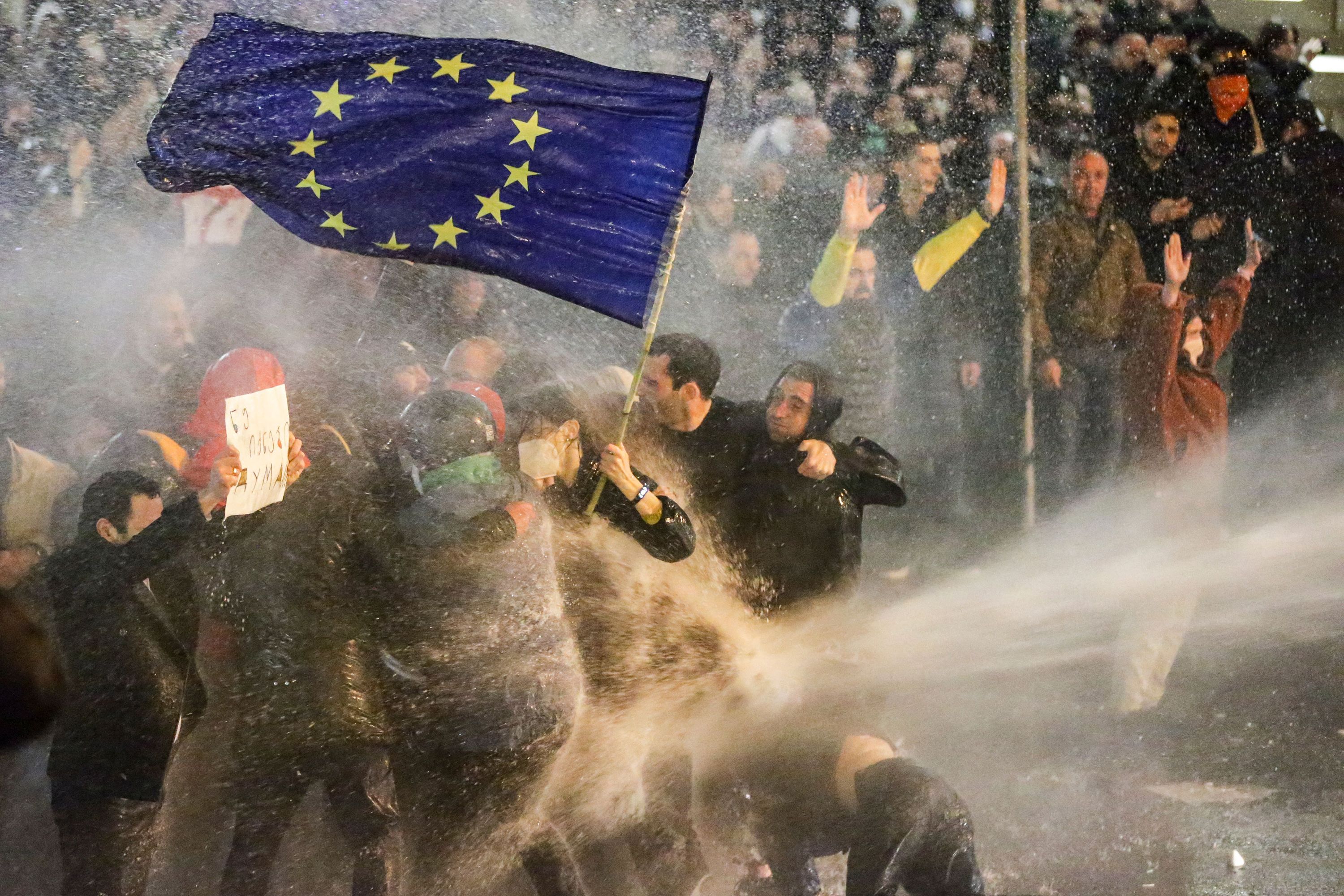 Protesters brandishing a European Union flag are sprayed by a water cannon as they clashes with riot police in Tbilisi, Georgia, on Tuesday, March 7.