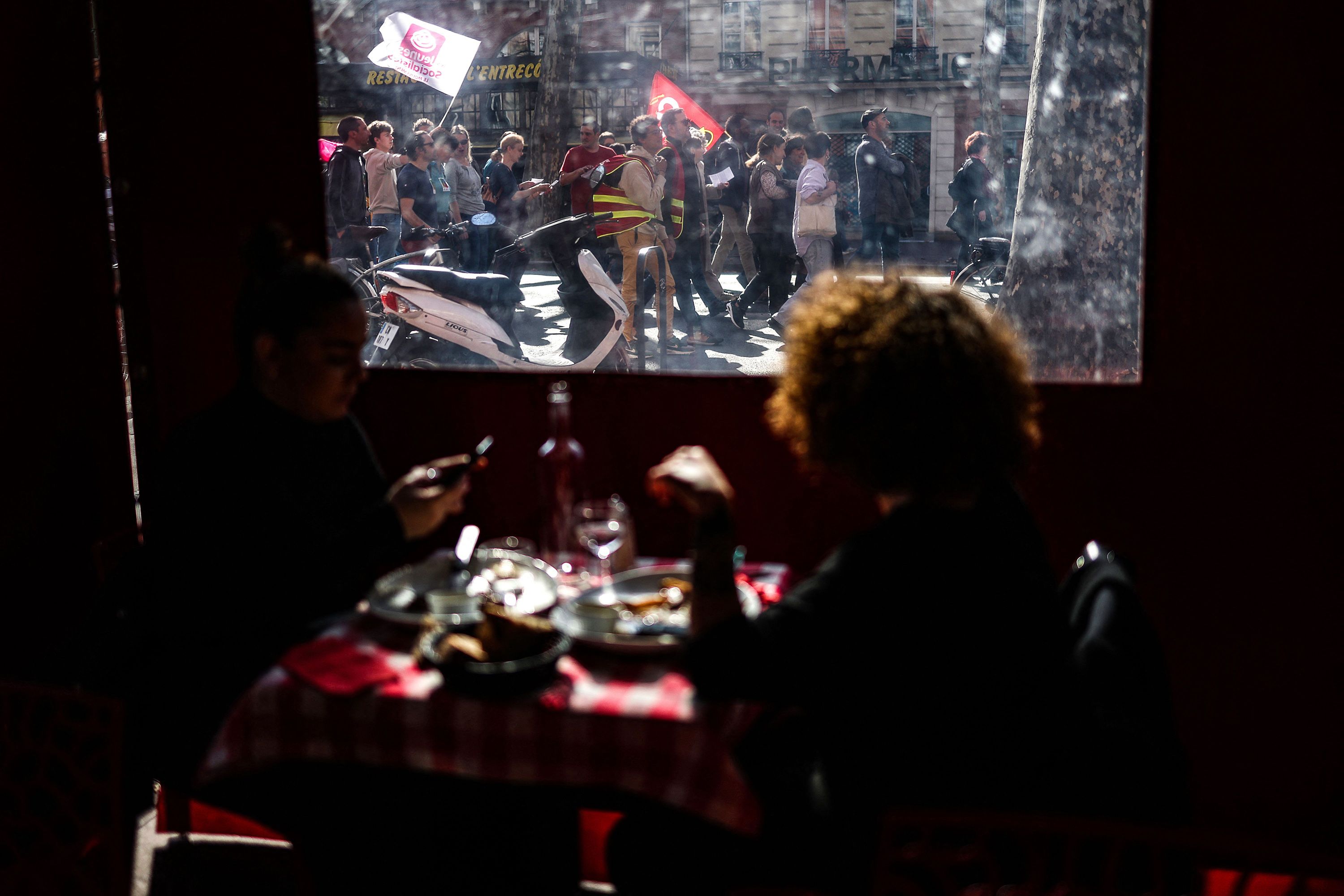 People eating lunch watch protesters march in Toulouse, France, on Thursday, March 9.