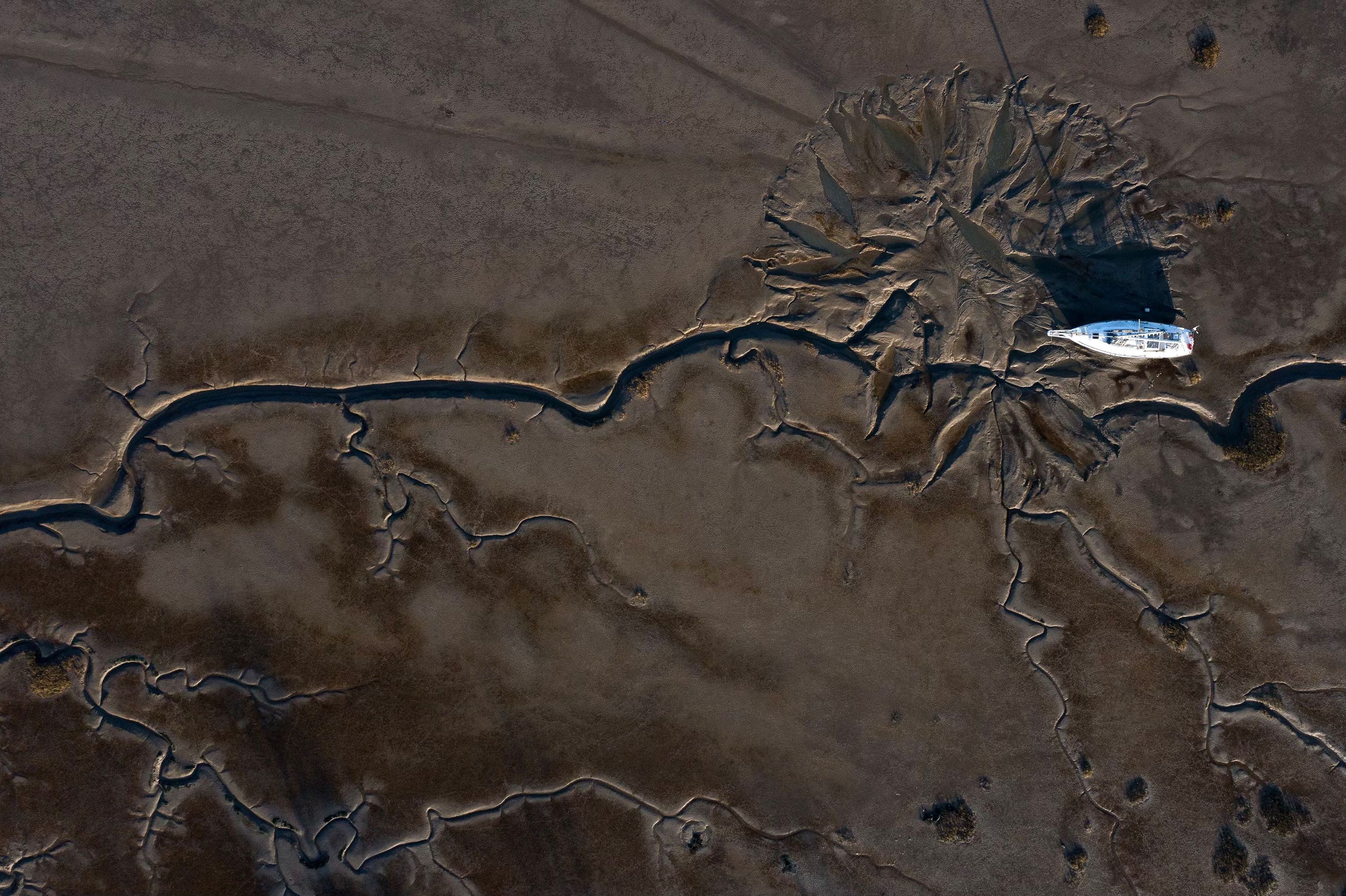 This aerial photo shows a yacht moored on mudflats, revealed during the low tide, after the River Medway ebbed near Gillingham, England, on Thursday, March 2.