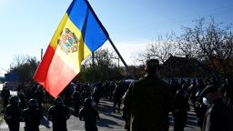 A man holds Moldovan national flag as special police officers patrol a street near a polling station during the second round of Moldova's presidential election in the town of Varnita at Moldova - Transnistrian border on November 15, 2020.