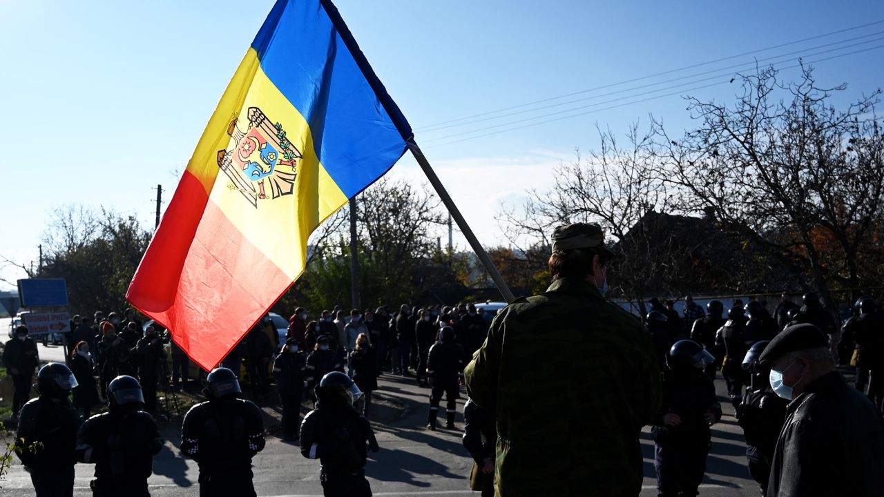 A man holds Moldovan national flag as special police officers patrol a street near a polling station during the second round of Moldova's presidential election in the town of Varnita.