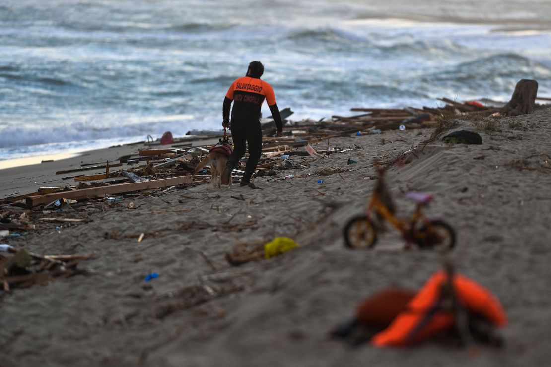 A policeman and his dog patrol the beach on February 26, 2023, where debris of a shipwreck was washed ashore after a migrants' boat sank off Italy's southern Calabria region.