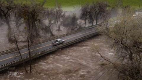 Sebuah truk pikap melintasi jembatan di atas Sungai Tule yang banjir pada 10 Maret di dekat Springville, California. 