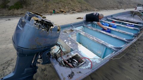 Boat salvager Robert Butler picks up a canister in one of the two boats sitting on Blacks Beach on March 12, 2023.